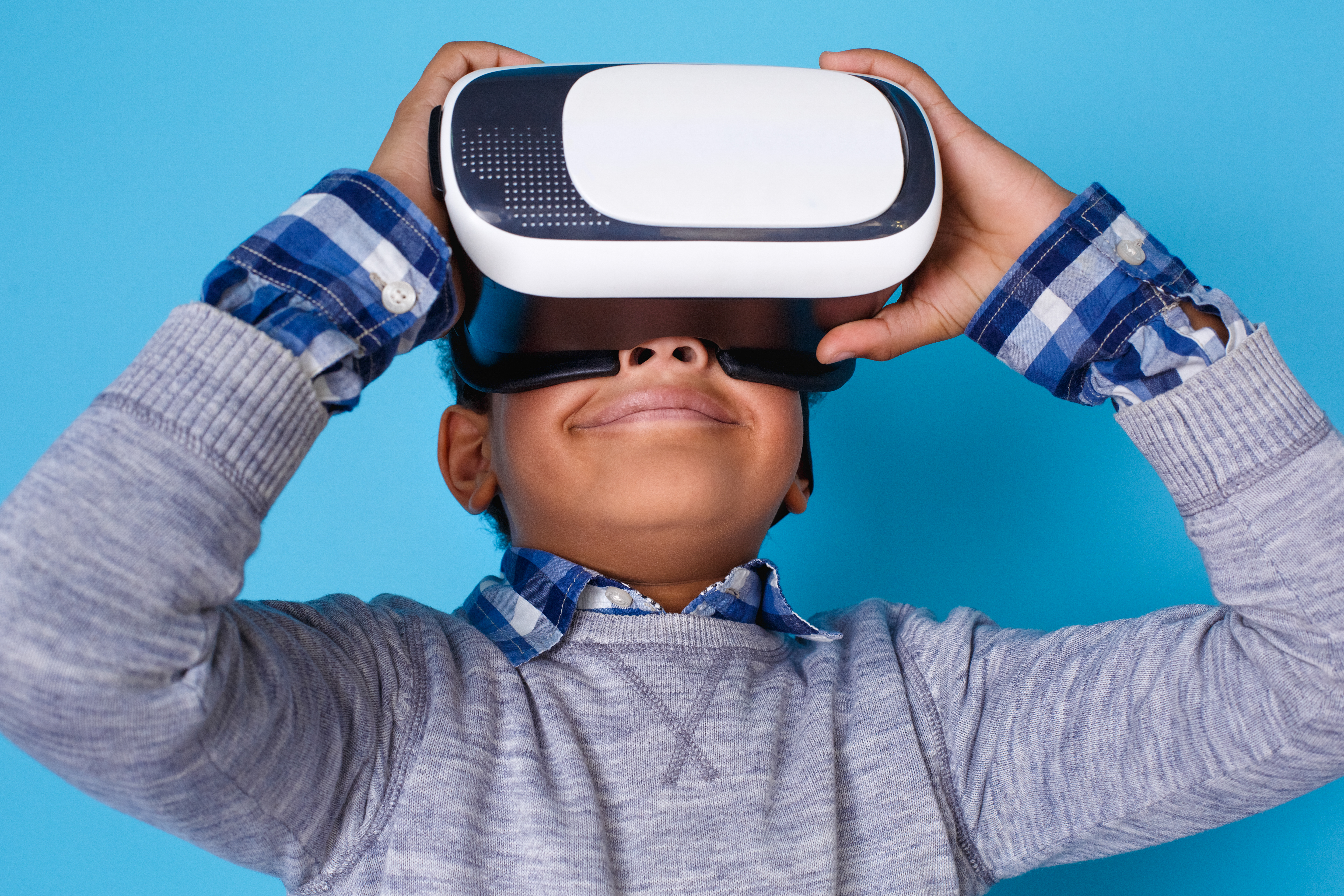 Young boy smiling with virtual reality goggles on.