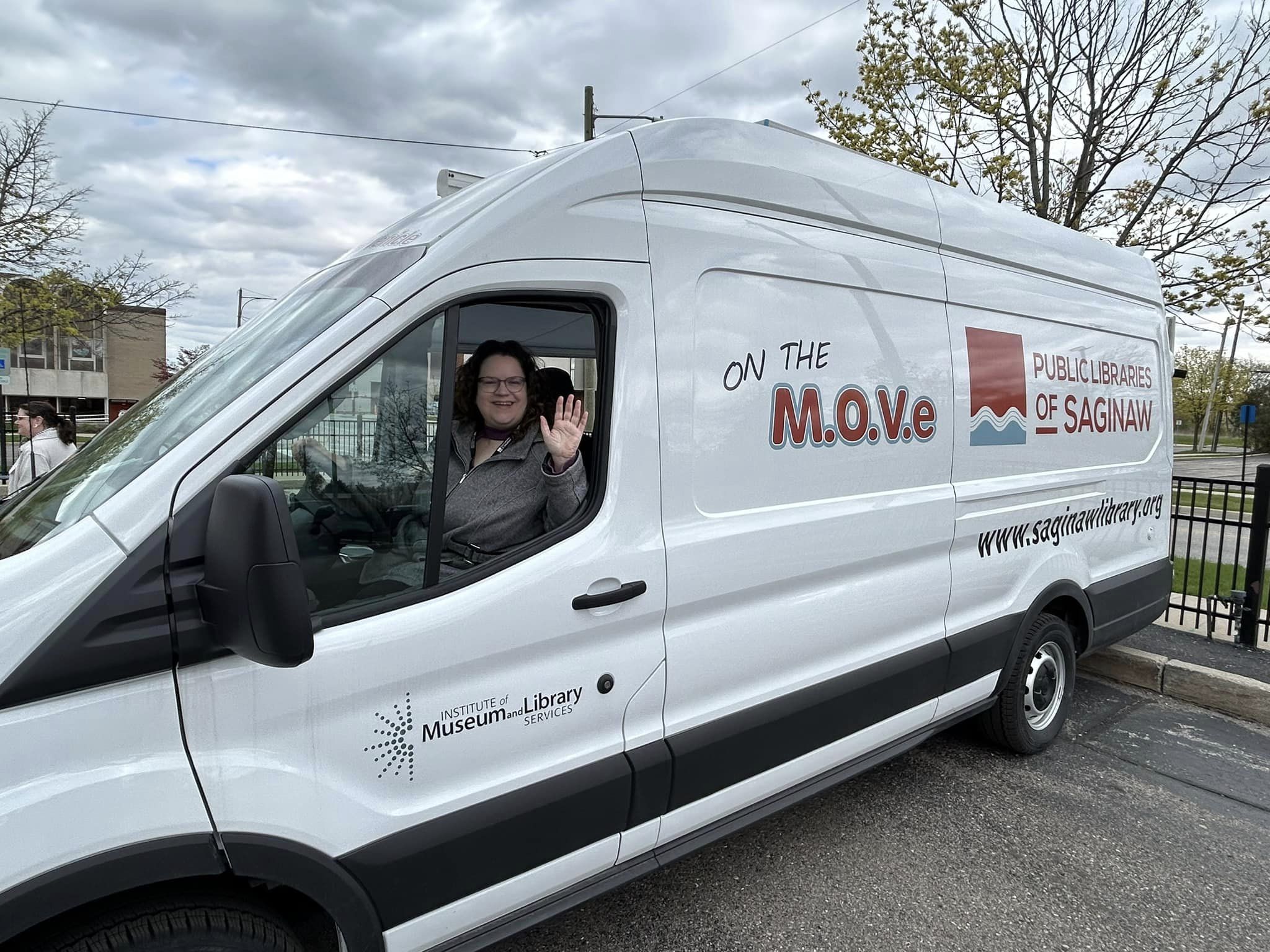 Outreach Librarian Beth Lasky waves from the Public Libraries of Saginaw's new Bookmobile