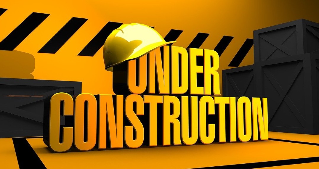 Black and yellow caution tape surround the words "Under Construction", with a yellow hard hat hanging of the letters "u" and "n" in the word under.