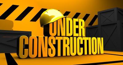 Black and yellow caution tape surround the words "Under Construction", with a yellow hard hat hanging of the letters "u" and "n" in the word under.
