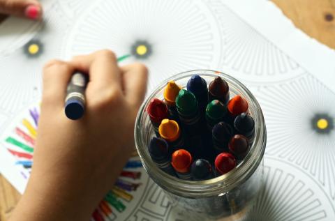 photo of child's hand and jar of crayons