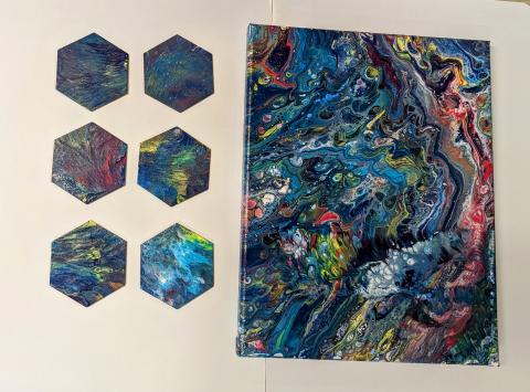 6 wooden tiles and a canvas that has been pour painted with a white base and then various colors for a rainbow effect.