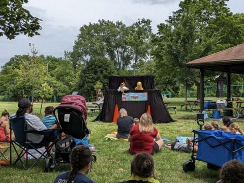 Families watch a puppet show in the park