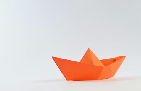 photo of orange paper folded into a boat - origami