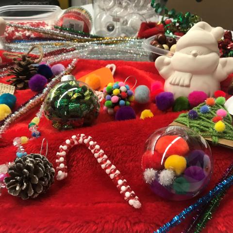 A picture with various craft supplies and holiday ornaments on a red background is shown.