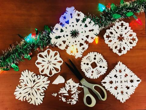 Paper snowflakes are shown with holiday lights and garland