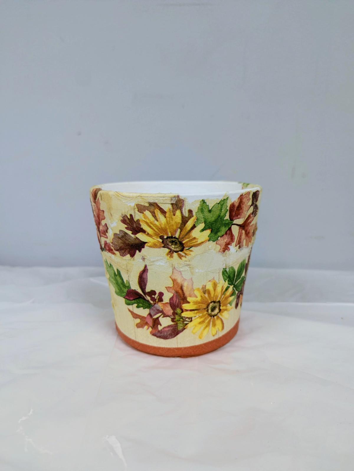 Clay flower pot decoupaged with yellow floral napkins.