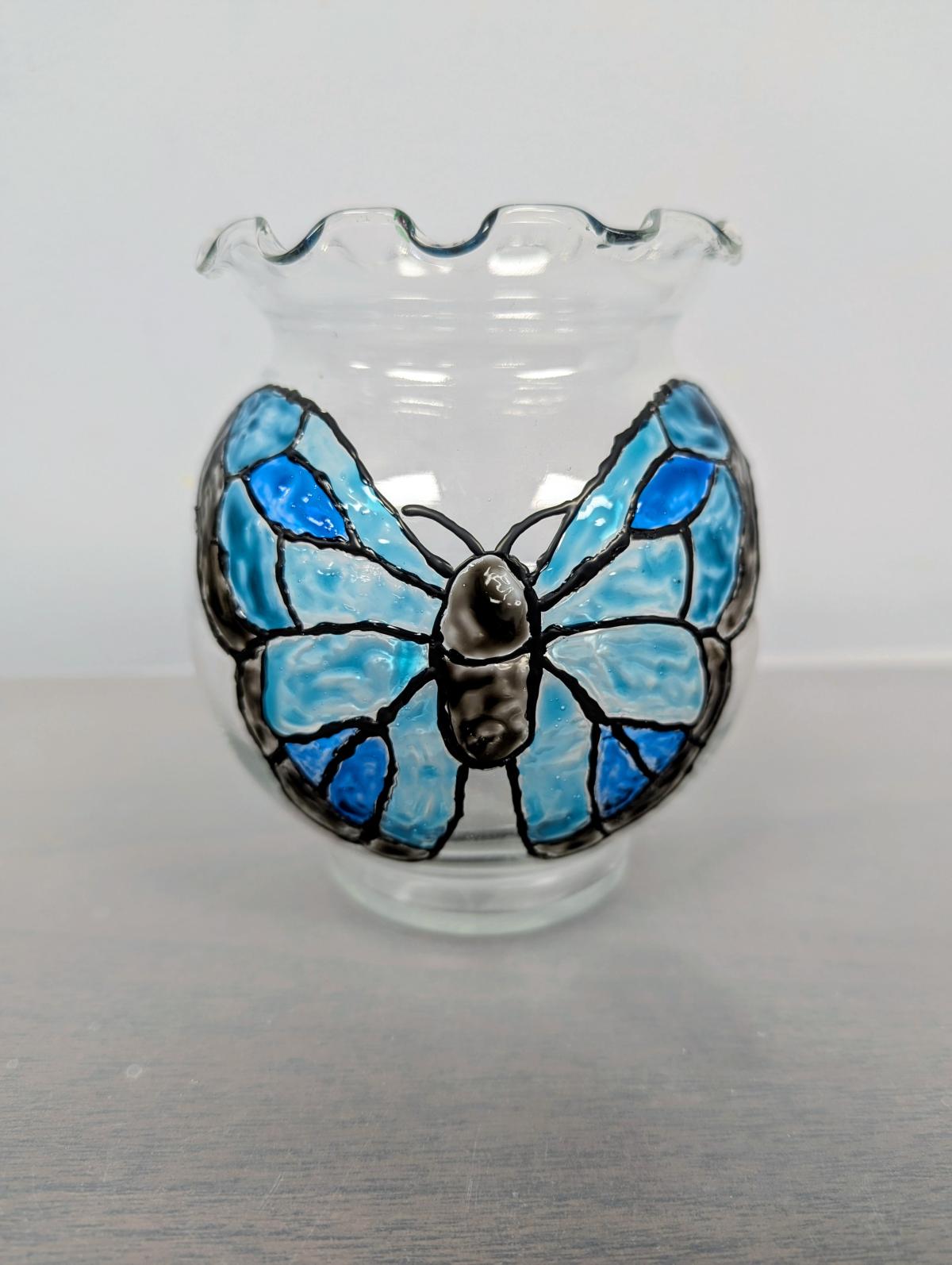 Clear glass bowl with a butterfly painted on it in shades of blues and black.