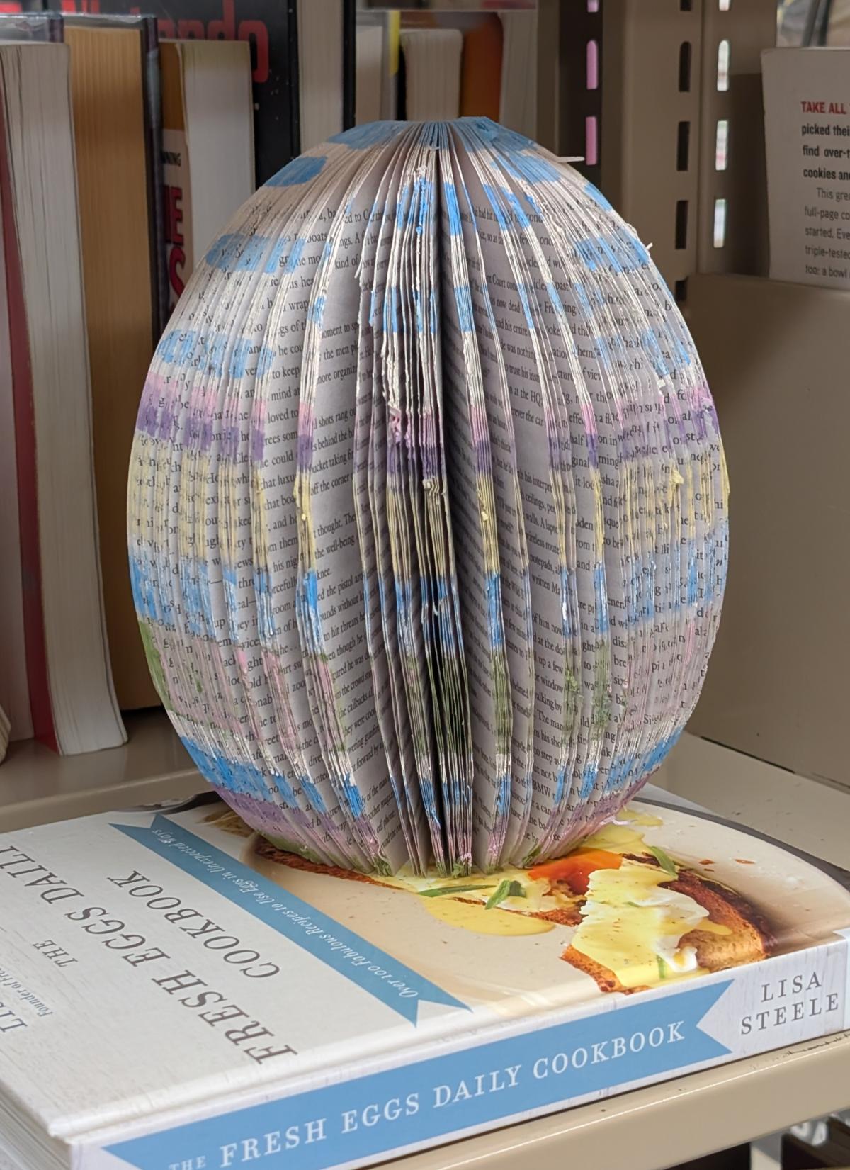 A book that is cut so it resembles an egg, painted with pastel colors. 
